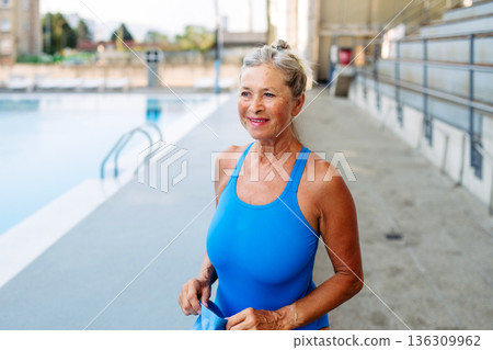 Older female swimmer getting ready for regular fitness swimming. Older female swimmer getting ready for regular fitness swimming. 136309962