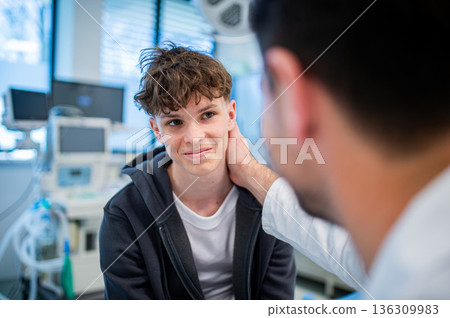 Teenage boy smiling during medical consultation after receiving positive health news. Teenage boy smiling during medical consultation after receiving positive health news. 136309983