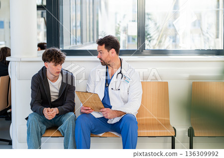 Doctor talking with teenage patient in hospital waiting room. Doctor talking with teenage patient in hospital waiting room. 136309992