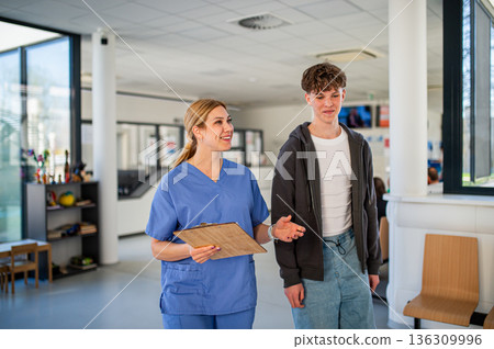 Doctor walking with teenage patient after successful medical procedure in hospital. Doctor walking with teenage patient after successful medical procedure in hospital. 136309996