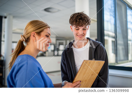Doctor talking with teenage boy in medical clinic. Doctor talking with teenage boy in medical clinic. 136309998