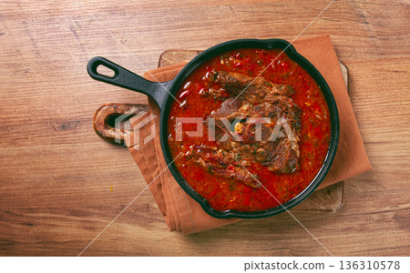 fried steak, veal neck on the bone, stewed with vegetables, in tomato sauce, cooking meat, in a cast-iron frying pan, top view, no people, 136310578