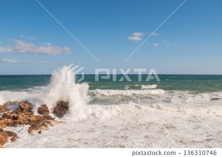 Cretan seascape in windy weather with strong surf and white foam on the sea. Cretan seascape in windy weather with strong surf and white foam on the sea. 136310746