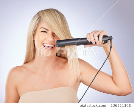Portrait, happy hair care and woman with straightener for a professional salon treatment. Smile, health and an excited young model or girl with an iron from hairdresser for a hairstyle on a backdrop Portrait, happy hair care and woman with straightener for a professional salon treatment. Smile, health and an excited young model or girl with an iron from hairdresser for a hairstyle on a backdrop 136311308