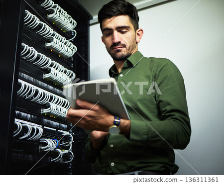 Engineer man, cable and server room with a tablet for programming, maintenance and software upgrade. Young male technician person with technology in data center for wire, hardware and internet Engineer man, cable and server room with a tablet for programming, maintenance and software upgrade. Young male technician person with technology in data center for wire, hardware and internet 136311361
