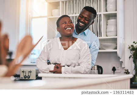 Hug, kitchen and happy black couple laugh, bond or enjoy quality time together, funny conversation or chat in Nigeria home. Love, marriage and African people humour, embrace and smile at comedy joke 136311483