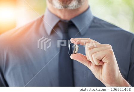 Hearing aid, hands and business man with disability for communication support, listening and medical innovation. Closeup of deaf worker with audiology implant to help sound waves, amplifier or volume Hearing aid, hands and business man with disability for communication support, listening and medical innovation. Closeup of deaf worker with audiology implant to help sound waves, amplifier or volume 136311498