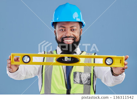Happy black man, portrait and architect with level for measuring in construction against a blue studio background. African male person, engineer or contractor smile holding tool for measurements 136311542