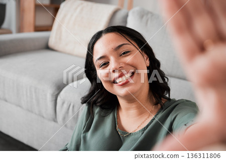 Selfie, happy and portrait of a woman in her living room relaxing, resting or chilling by the sofa. Happiness, smile and young female person from Mexico taking a picture at her modern home apartment. 136311806