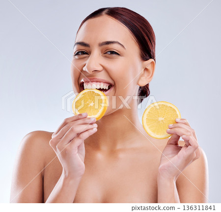 Woman, eating orange and nutrition with beauty, skincare and natural cosmetics on white background. Happy, female model and citrus fruit, vitamin c and healthy food, skin glow and portrait in studio 136311841