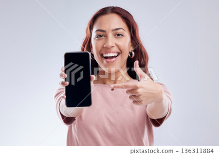 Happy woman is pointing at phone screen, mockup and marketing, mobile app ads on white background. Website promo, advertising and female ambassador in portrait with social media branding in studio Happy woman is pointing at phone screen, mockup and marketing, mobile app ads on white background. Website promo, advertising and female ambassador in portrait with social media branding in studio 136311884