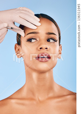 Skin injection, woman and concern of plastic surgery and collagen skincare in studio. Needle, beauty and female person with blue background with cosmetics, filler and wellness for dermatology Skin injection, woman and concern of plastic surgery and collagen skincare in studio. Needle, beauty and female person with blue background with cosmetics, filler and wellness for dermatology 136311945