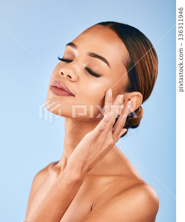 Woman, touch face and beauty, makeup and skincare with shine and manicure isolated on blue background. Female model, hand with dermatology and facial, healthy skin glow and cosmetic care in a studio 136311946
