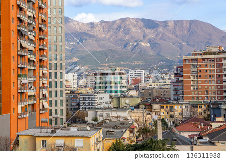Residential apartment buildings and dense urban housing with mountains in background during daylight in capital city Tirana, Albania Residential apartment buildings and dense urban housing with mountains in background during daylight in capital city Tirana, Albania 136311988