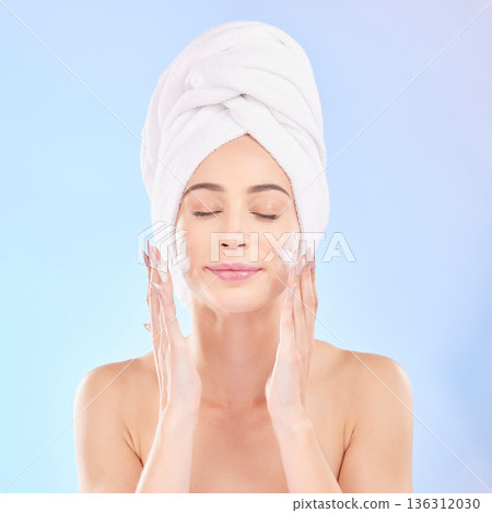 Face, skincare and woman with soap, towel and isolated in studio on a blue background. Eyes closed, cosmetic and model washing, cleaning or hygiene with facial foam for health, dermatology or beauty 136312030