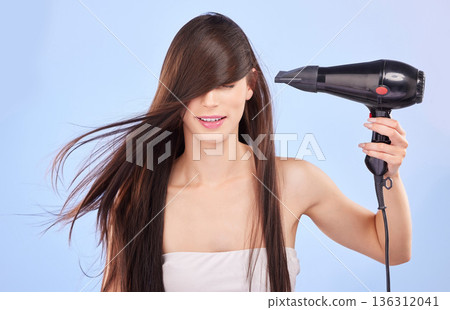 Hair, dryer and woman in studio for beauty, cosmetics and shine on blue background. Female model, heating tools and electrical appliance for wind, clean haircare and smooth aesthetic texture in salon Hair, dryer and woman in studio for beauty, cosmetics and shine on blue background. Female model, heating tools and electrical appliance for wind, clean haircare and smooth aesthetic texture in salon 136312041