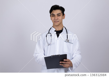 Doctor in white coat holding medical chart and smiling Doctor in white coat holding medical chart and smiling 136312084
