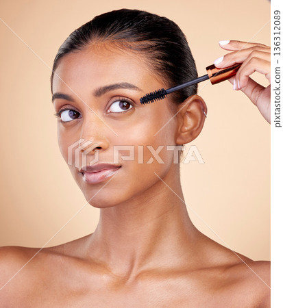 Beauty, makeup and mascara with face of woman in studio for cosmetics, eyelashes and glamour. Self care, application and tools with female model on brown background for product, volume and glow Beauty, makeup and mascara with face of woman in studio for cosmetics, eyelashes and glamour. Self care, application and tools with female model on brown background for product, volume and glow 136312089