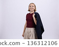 Businesswoman in suit jacket holding blazer over shoulder 136312106