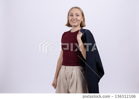 Businesswoman in suit jacket holding blazer over shoulder 136312106