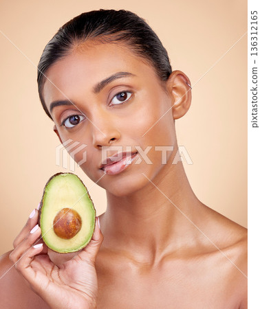 Avocado, skincare and woman in portrait for healthy face and natural beauty on studio brown background. Young indian person or model with green fruits, vitamin c benefits and dermatology or cosmetics Avocado, skincare and woman in portrait for healthy face and natural beauty on studio brown background. Young indian person or model with green fruits, vitamin c benefits and dermatology or cosmetics 136312165