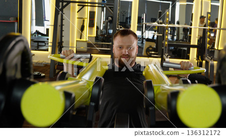 Man training on chest press machine in gym 136312172