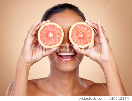 Grapefruit, beauty and eyes of happy woman in studio, vitamin c nutrition or natural glow. Face of female model, healthy skincare or smile with citrus fruits, eco dermatology or sustainable cosmetics Grapefruit, beauty and eyes of happy woman in studio, vitamin c nutrition or natural glow. Face of female model, healthy skincare or smile with citrus fruits, eco dermatology or sustainable cosmetics 136312174