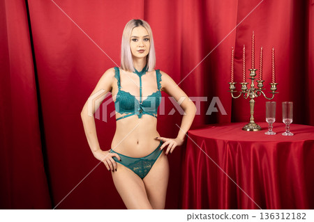 Woman in green lingerie standing in red room Woman in green lingerie standing in red room 136312182