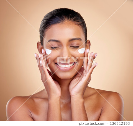 Facial cream, skincare smile of woman for aesthetic shine, cosmetics or clean dermatology on studio background. Happy indian female model, face lotion or sunscreen product for healthy beauty glow 136312193