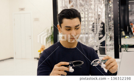 Man holding glasses frame in hands in store 136312198