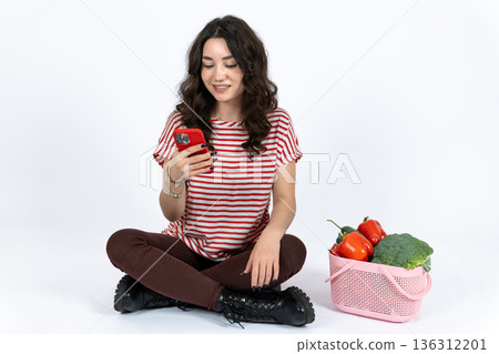 Young woman sitting and eating red apple in studio Young woman sitting and eating red apple in studio 136312201