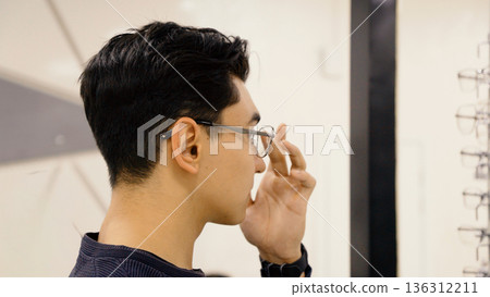 Man adjusting eyewear frame near shop display Man adjusting eyewear frame near shop display 136312211