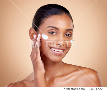 Face, cream and portrait of indian woman, skincare cosmetics and aesthetic dermatology on studio background. Happy young female model, lotion and facial sunscreen for clean beauty, glow and self care 136312226