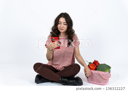 Woman sitting on floor with smartphone and apples Woman sitting on floor with smartphone and apples 136312227