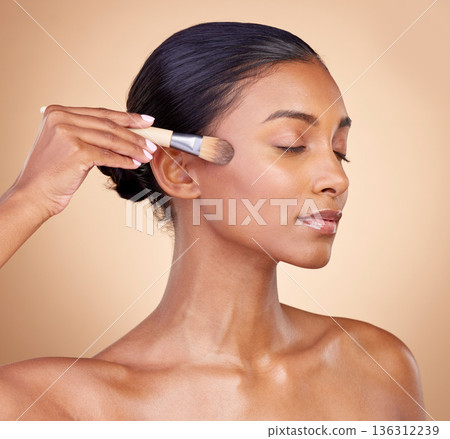 Beauty, makeup and cosmetics with woman and brush in studio for facial, foundation and self care. Relax, product and tools with face of model on brown background for glow, skincare and dermatology 136312239