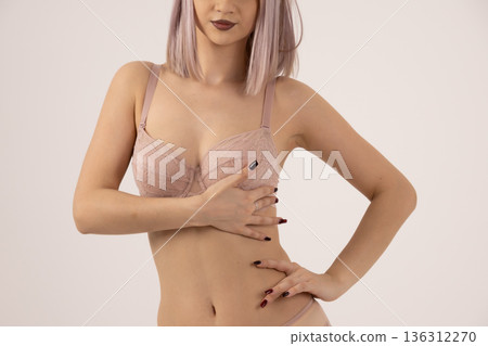 Young woman holding her hair in beige lingerie 136312270