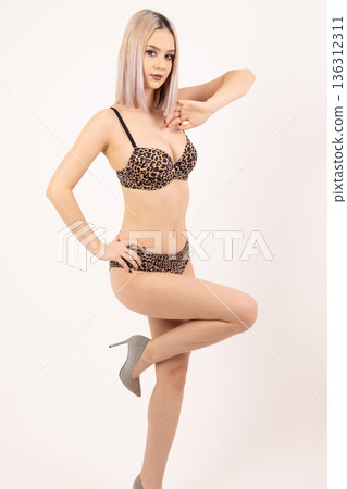 Young blonde woman posing with hands on hips and one leg raised 136312311