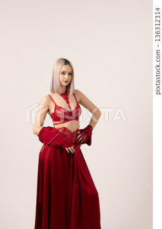 Woman in red evening dress sitting and posing in studio Woman in red evening dress sitting and posing in studio 136312314