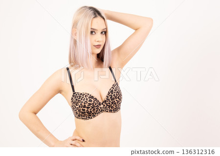 Fit woman in leopard print lingerie posing with hands on head 136312316