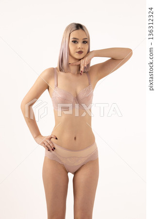 Woman in beige underwear standing on white background 136312324