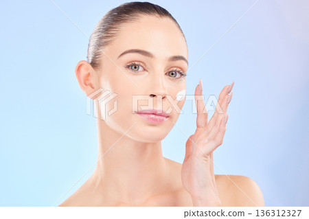 Face, skincare and woman with sunscreen in studio isolated on a blue background. Portrait, dermatology and serious model with cream, beauty cosmetic or moisturizer for health, aesthetic or wellness 136312327