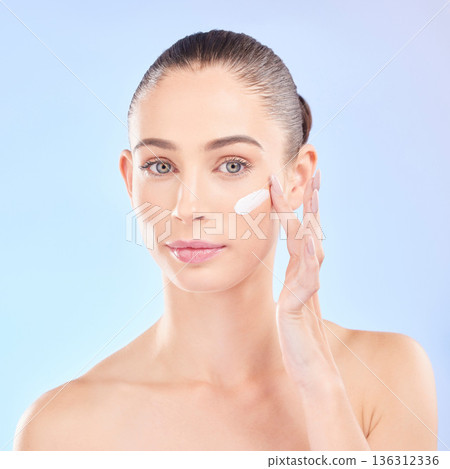 Face, skincare and woman with cream in studio isolated on a blue background. Portrait, dermatology and serious model with creme, cosmetic or sunscreen moisturizer for health, aesthetic or wellness Face, skincare and woman with cream in studio isolated on a blue background. Portrait, dermatology and serious model with creme, cosmetic or sunscreen moisturizer for health, aesthetic or wellness 136312336
