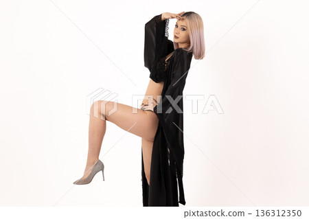Woman in black lingerie and gown posing with one leg up 136312350
