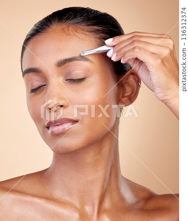 Beauty, face or woman with tweezers for eyebrow maintenance, hair removal or cosmetic routine. Morning self care, grooming product or relax studio person with facial plucking tool on brown background 136312374