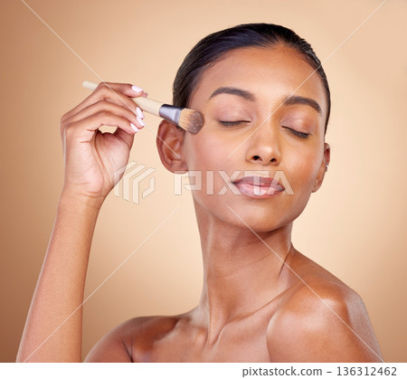 Beauty, makeup and skincare with woman and brush in studio for facial, foundation and self care. Cosmetics, product and tools with face of model on brown background for glow, relax and dermatology 136312462
