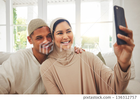 Selfie, Islam and happy couple on couch with smile, culture and love in living room in Indonesia. Marriage, man and woman in hijab on sofa together with respect, religion and photo for social media. Selfie, Islam and happy couple on couch with smile, culture and love in living room in Indonesia. Marriage, man and woman in hijab on sofa together with respect, religion and photo for social media. 136312757