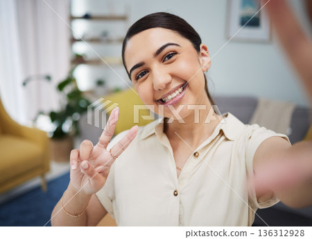 Happy woman, portrait and peace for selfie in home, video call or live streaming vlog in living room. Face of young female gen z show v sign, hand emoji and memory for social media or profile picture Happy woman, portrait and peace for selfie in home, video call or live streaming vlog in living room. Face of young female gen z show v sign, hand emoji and memory for social media or profile picture 136312928