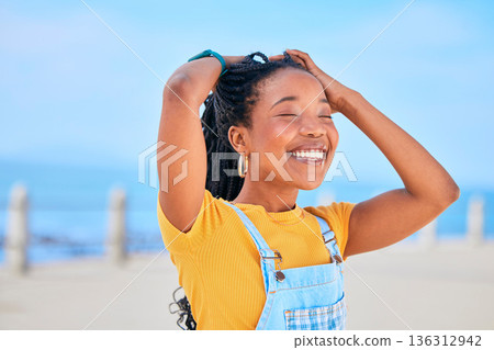 Face, smile and hair with a black woman on a blurred background by the ocean during summer vacation. Eyes closed, happy and braids with a young female person outdoor on the promenade for a holiday Face, smile and hair with a black woman on a blurred background by the ocean during summer vacation. Eyes closed, happy and braids with a young female person outdoor on the promenade for a holiday 136312942