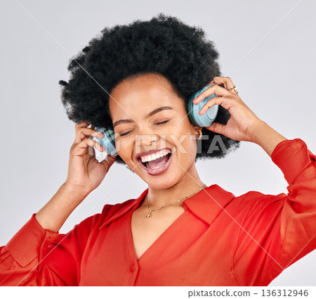 Excited black woman, music and headphones in studio for podcast subscription on white background. Face of happy female model singing while listening to audio, streaming sound or hearing song on radio Excited black woman, music and headphones in studio for podcast subscription on white background. Face of happy female model singing while listening to audio, streaming sound or hearing song on radio 136312946