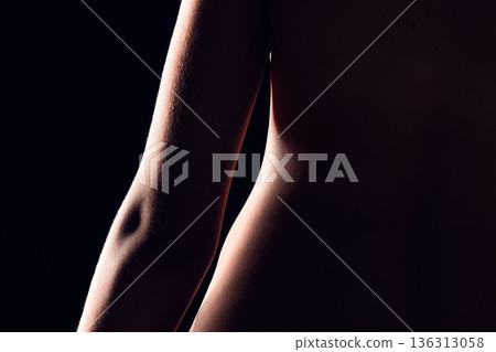 Beauty, body and person on black background for creative lighting, shadow and silhouette. Aesthetic, skincare and closeup of waist in dark studio with macro of skin for art deco, wellness and glow 136313058